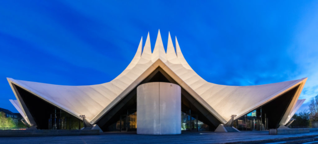 View of the event venue Tempodrom during the blue hour, Kreuzberg neighborhood, Berlin, Germany. It was inaugurated in 1980 next to the Berlin Wall on the west side of Potsdamer Platz and was housed in a large circus tent. After several changes of location it got a permanent building in 2002 and has today three performance spaces with a capacity of 3,800 people in the main one.