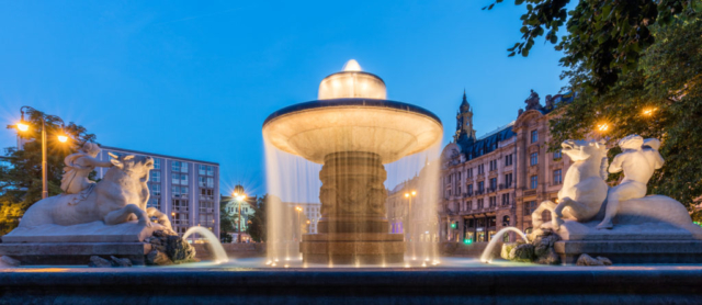 The monumental Wittelsbacher fountain in the northern part of central Munich, in Bavaria, Germany. The sculpture on the left is of a woman seated on a bull, holding a bowl, and depicts the healing qualities of water; on the right, a man sits astride a horse and hurls a rock, representing water's destructive power. Built between 1893 and 1895, the design follows drawings of the sculptor Adolf von Hildebrand.