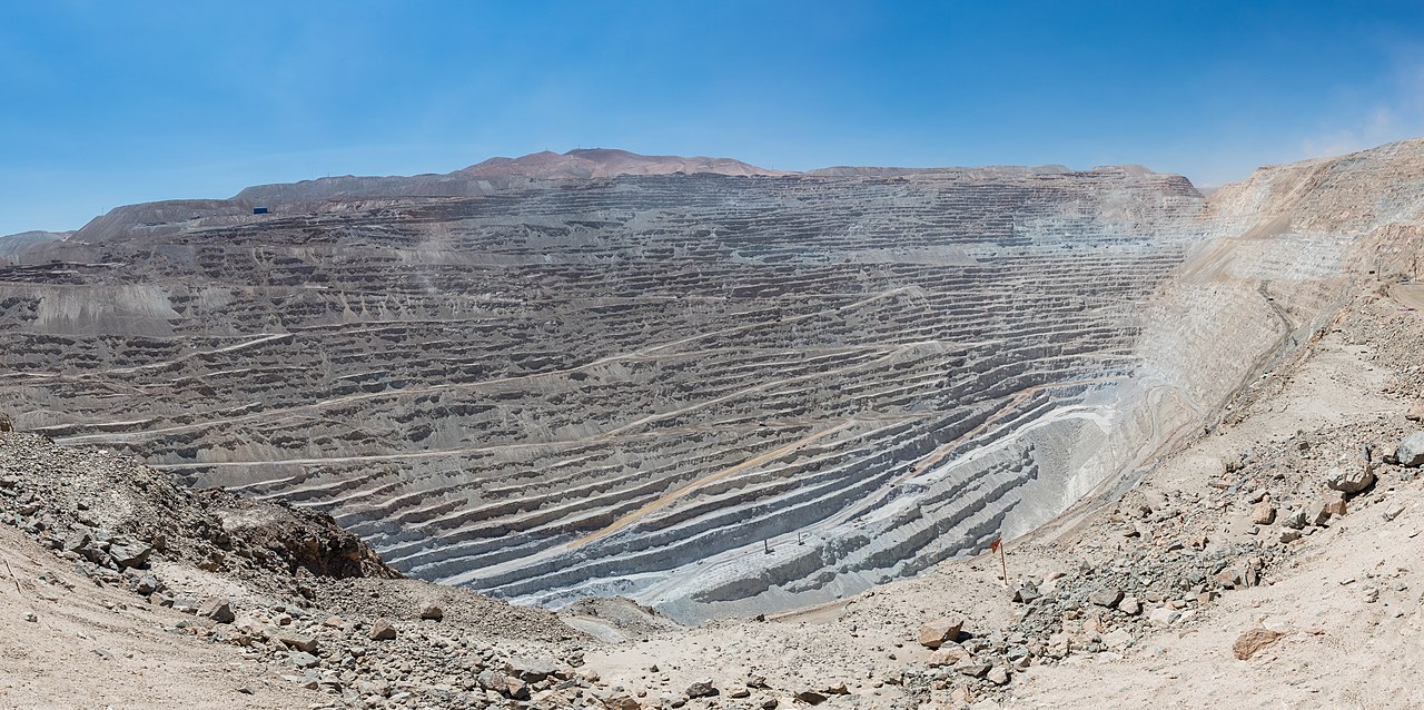 Panoramic view of Chuquicamata, a state-owned copper mine located at 2,850 metres (9,350 ft) above sea level just outside Calama, north of Chile. It is by excavated volume the largest open pit copper mine in the world. The huge hole was started in 1882 as a mine to extract gold and copper. It is 4.5 kilometres (2.8 mi) long, 3.5 kilometres (2.2 mi) wide and with a depth of 850 metres (2,790 ft) it is the second deepest open-pit mine in the world (after Bingham Canyon Mine in Utah, USA). Note: to get a feeling of the scale spot out a haul truck, which is 9.5 metres (31 ft) long and 4.5 metres (15 ft) high.